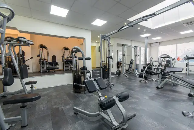 Sala de musculação com máquinas e bancos